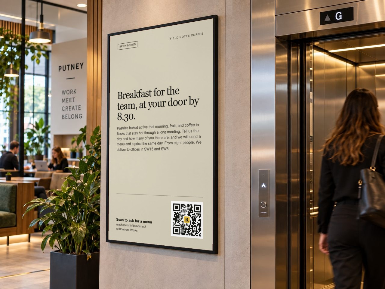 A framed poster by an office lift with a café's breakfast offer and its QR code