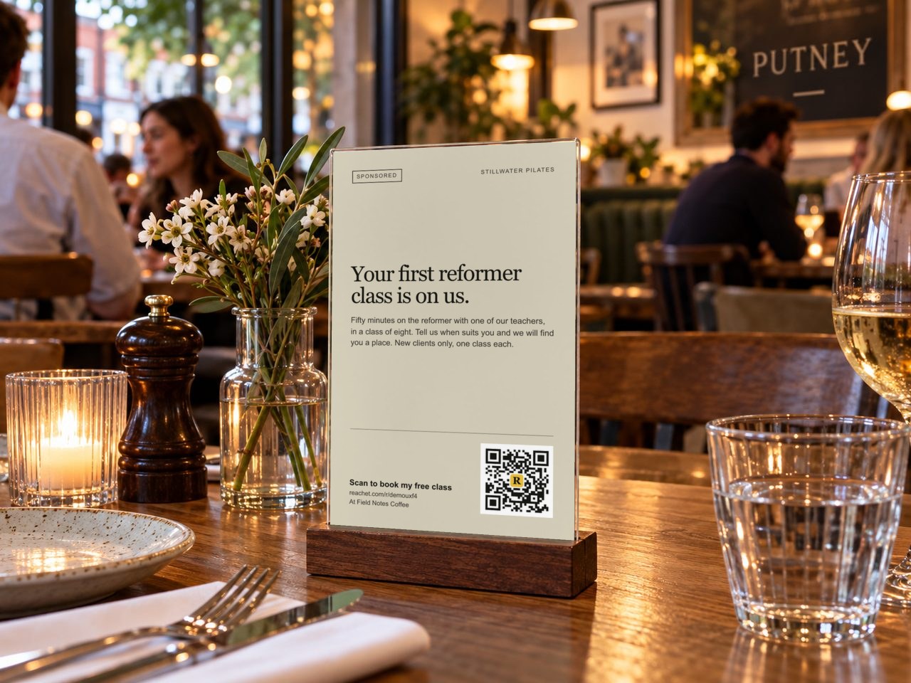 A table tent on a café table with a Pilates studio's offer and its QR code