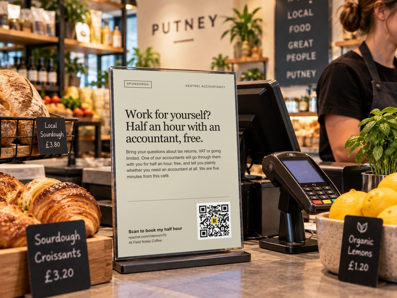 A card beside a café till with an accountant's offer and its QR code